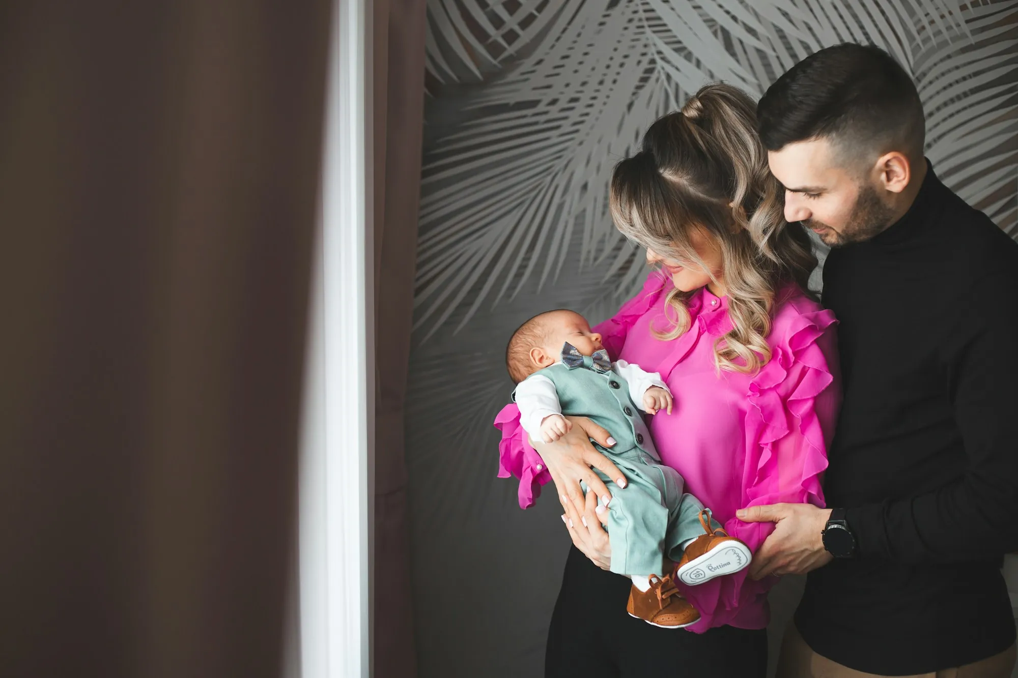 Parents holding their newborn in a softly lit room