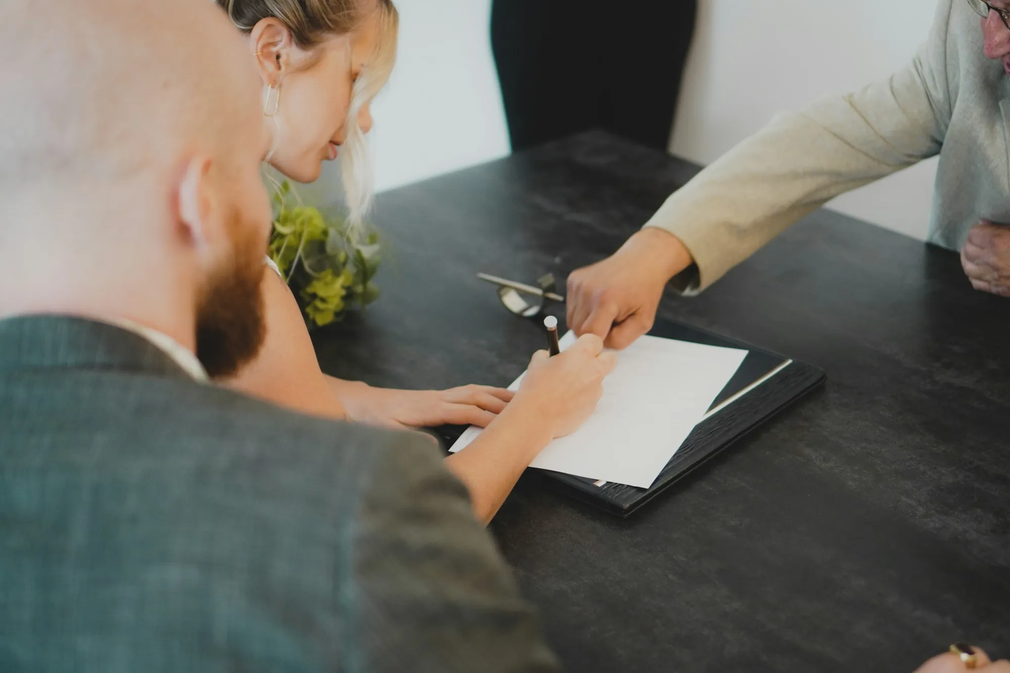 Couple signing paperwork across a dark table while planning laddered term life insurance in Lake Bluff